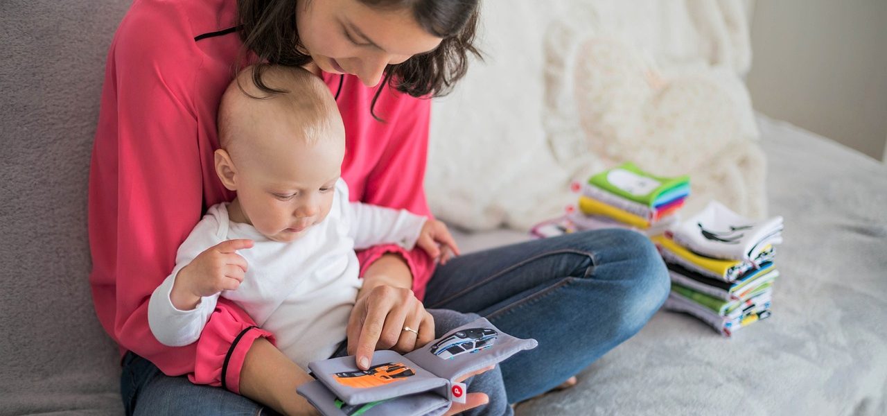 Mother reading books to her baby with a soft, cozy setting.