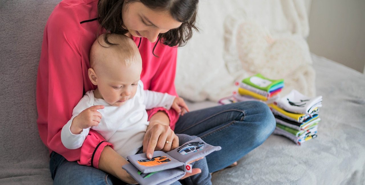 Mother reading books to her baby with a soft, cozy setting.