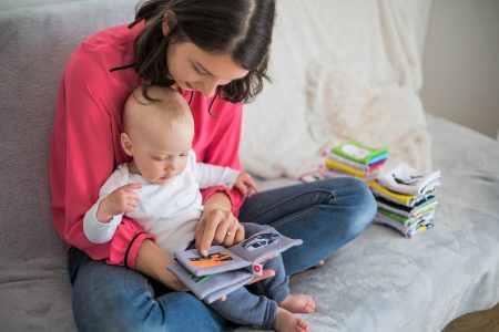 Mother reading books to her baby with a soft, cozy setting.